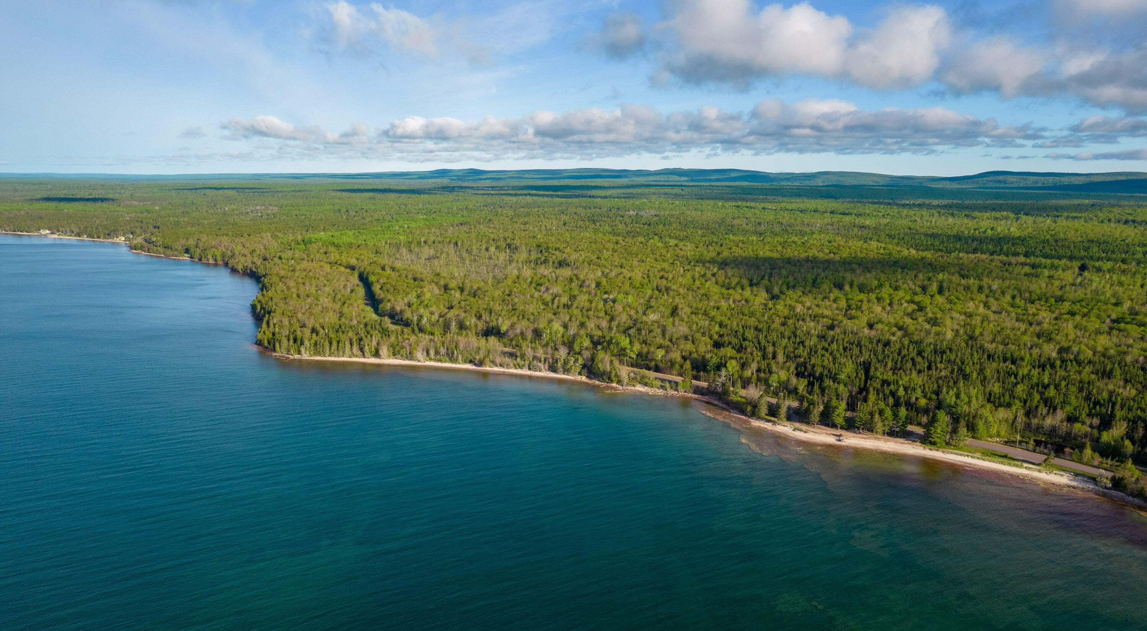 The Little Betsy Shoreline in the Keweenaw Peninsula. The water of Lake Superior is blue and the sky is clear. 