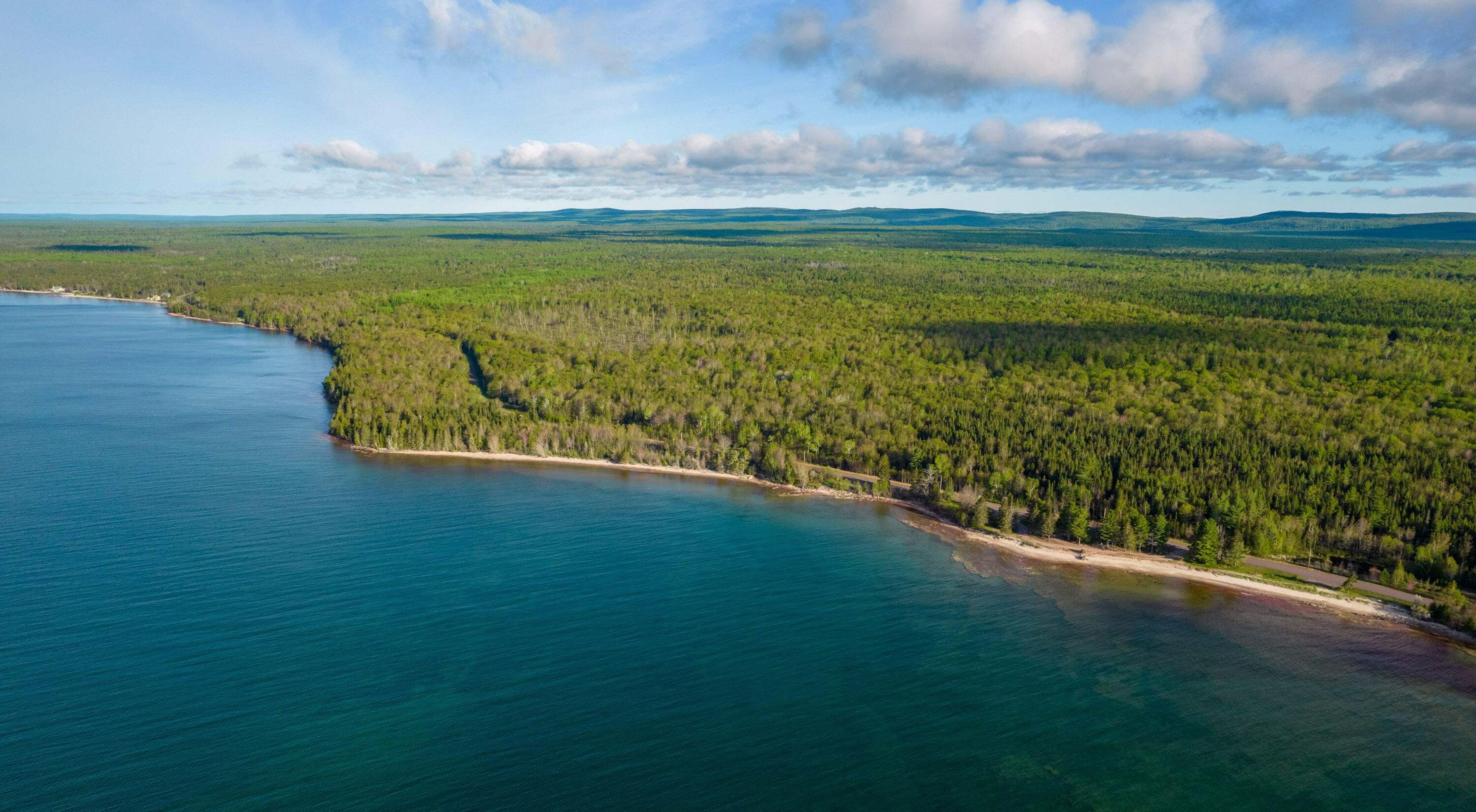  The Little Betsy Shoreline on a clear day. The water of Lake Superior is a bright blue and a vast forest extends from the shore.