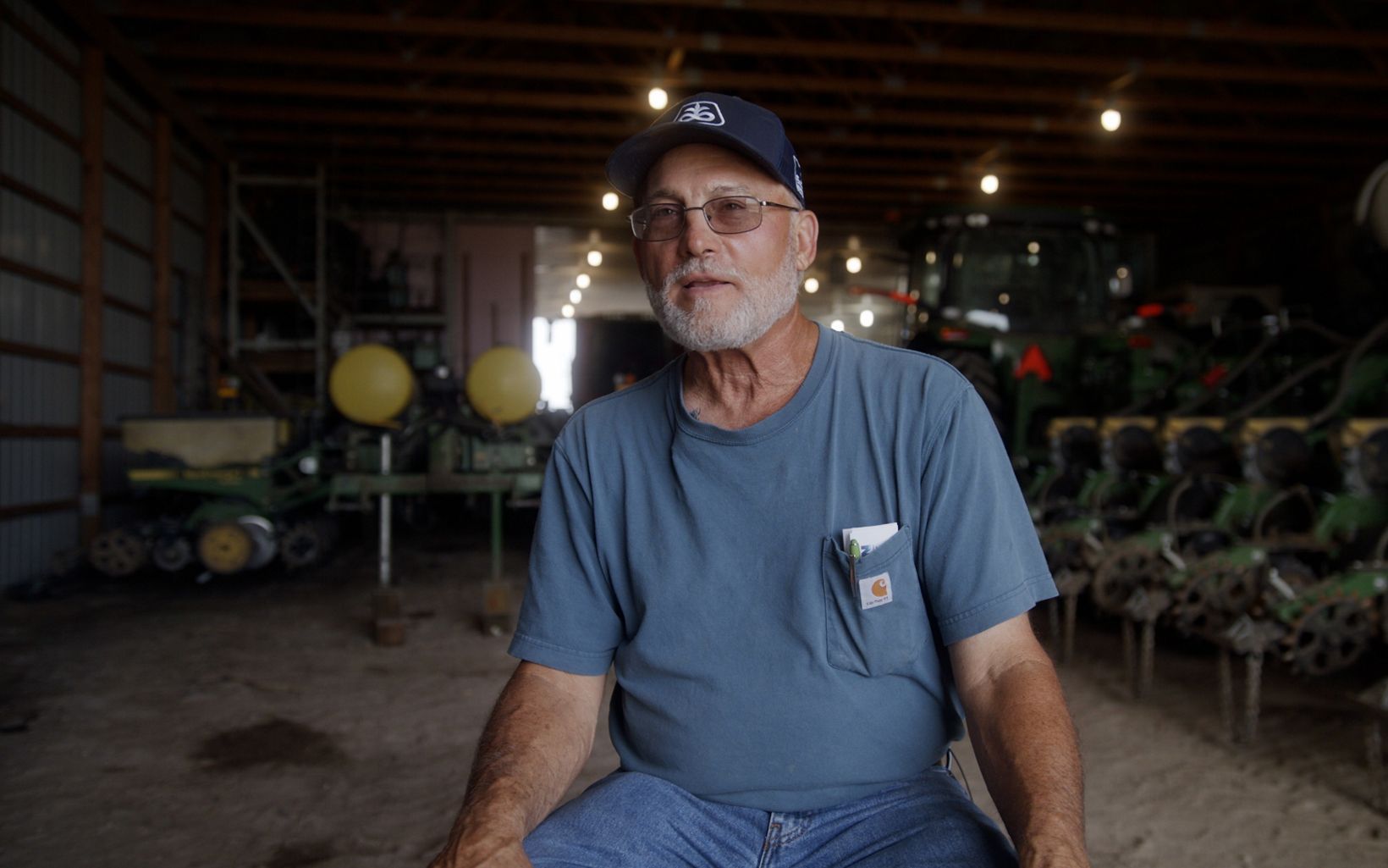 Don Morse sits in a barn, surrounded by equipment.