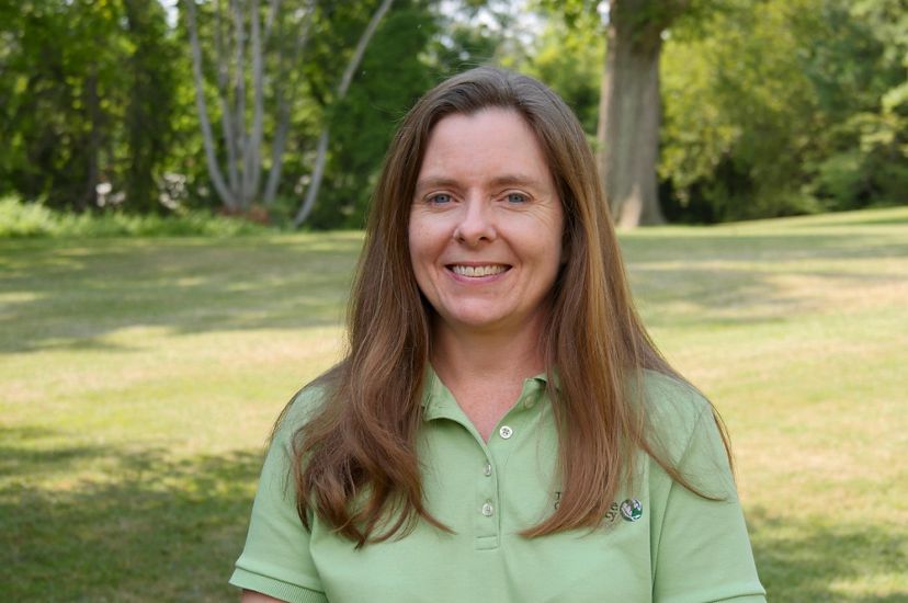 Michelle Canick headshot. A smiling woman in a pale green shirt stands in an open park space with trees behind her.