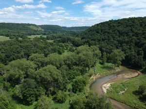 River winding through a forest with patches of open grassland in Minnesota’s driftless area.