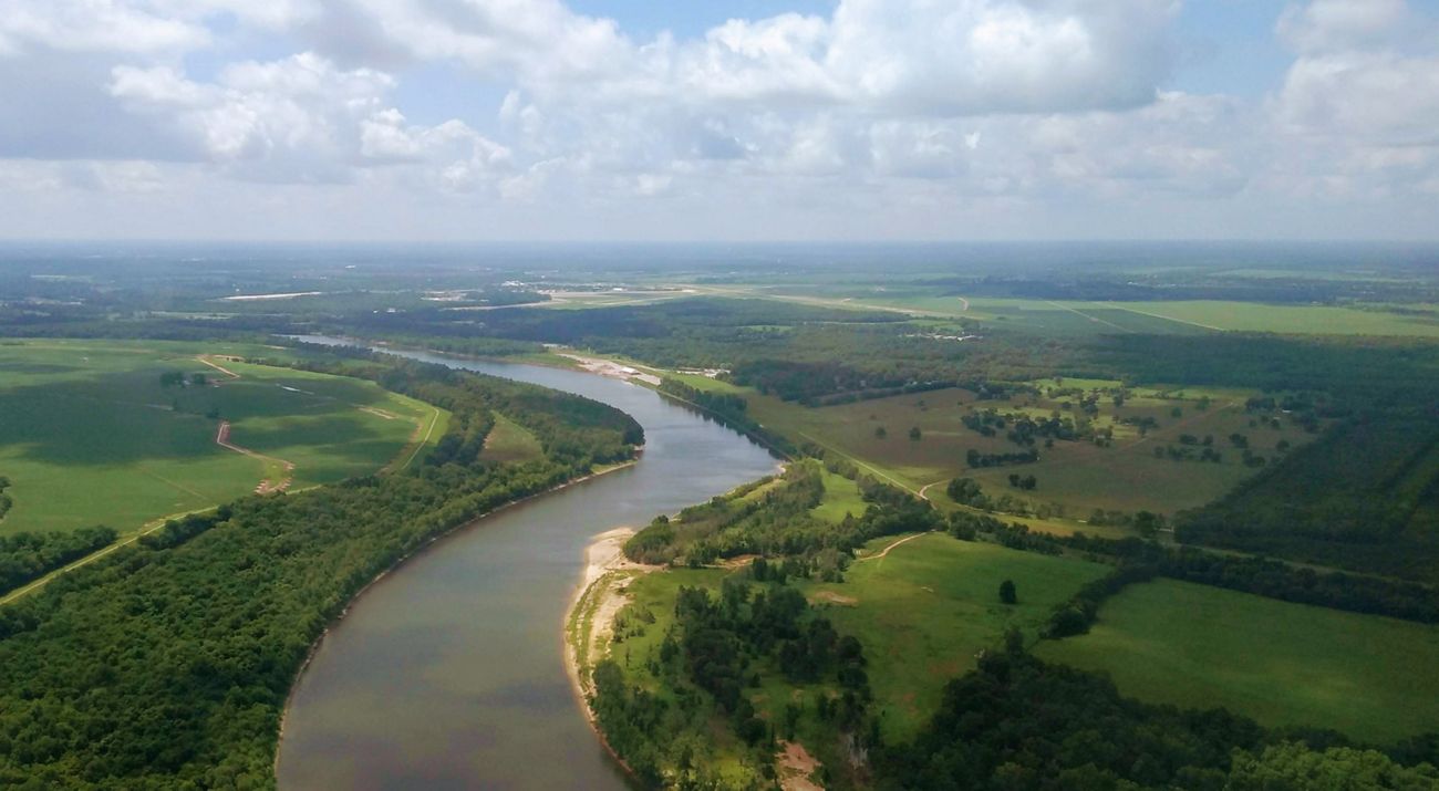 Aerial view of the Mississippi River as it bends and twists through an open, green landscape.