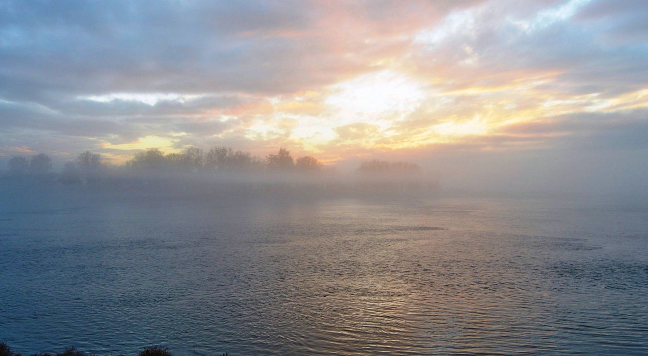 A pink sunrise frames a calm river.