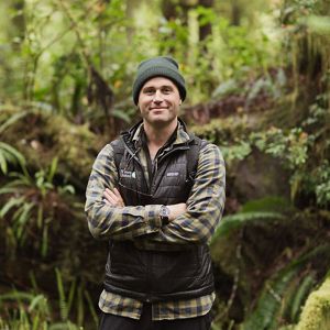 outdoor headshot of a smiling white man with dark hair