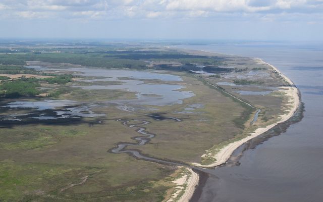 An aerial view of land meeting a body of water.