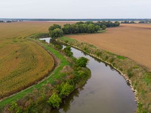 Aerial view of golden farm fields on either side of a winding river.