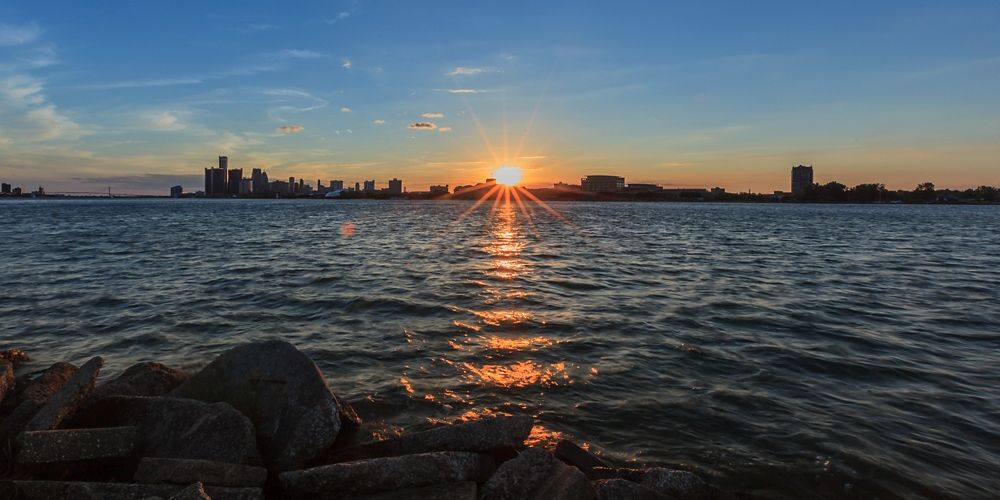 View from the water of sun setting behind the Detroit skyline.