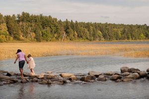 Two children walk across the headwaters of the Mississippi River at Lake Itasca