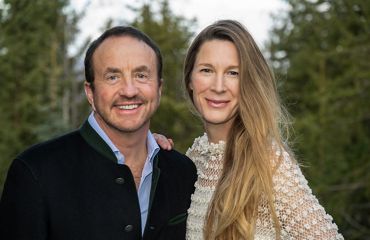 Two people standing in front of trees.