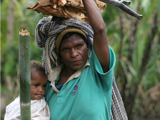A woman holding a baby and firewood.
