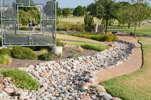A pathway of tan and grey rocks linked with green plants and grass.