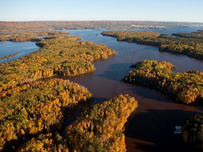 A river view from overhead, with trees showing yellow and orange fall color on the banks.