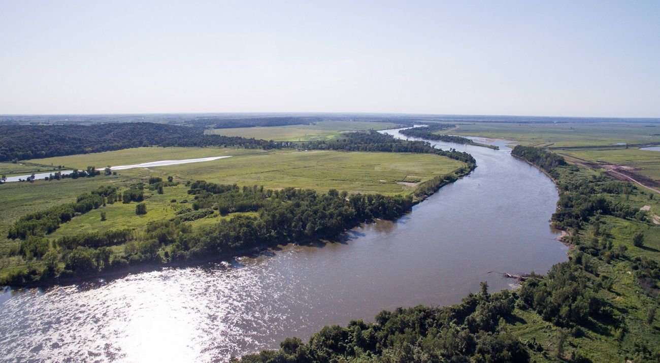 Sun shining on a river flowing through agricultural lands.