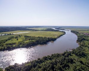 Sun shining on a river flowing through agricultural lands.