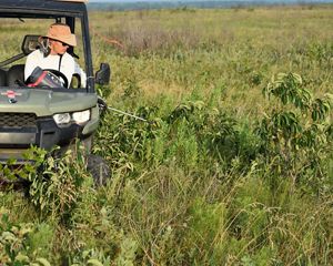A man sits in a UTV on an open prairie spraying invasive plants.