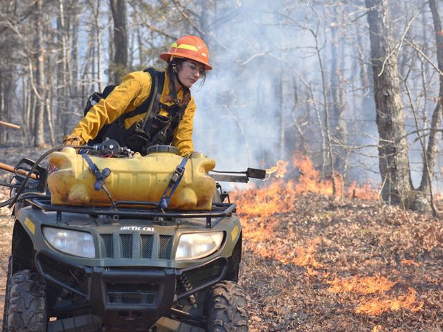 A woman on a 4-wheeler participates in a prescribed fire.