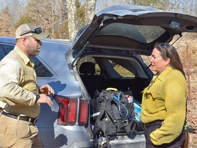 Ryan Gauger and Kelly Martin standing on a rural road have a discussion next to a parked car.