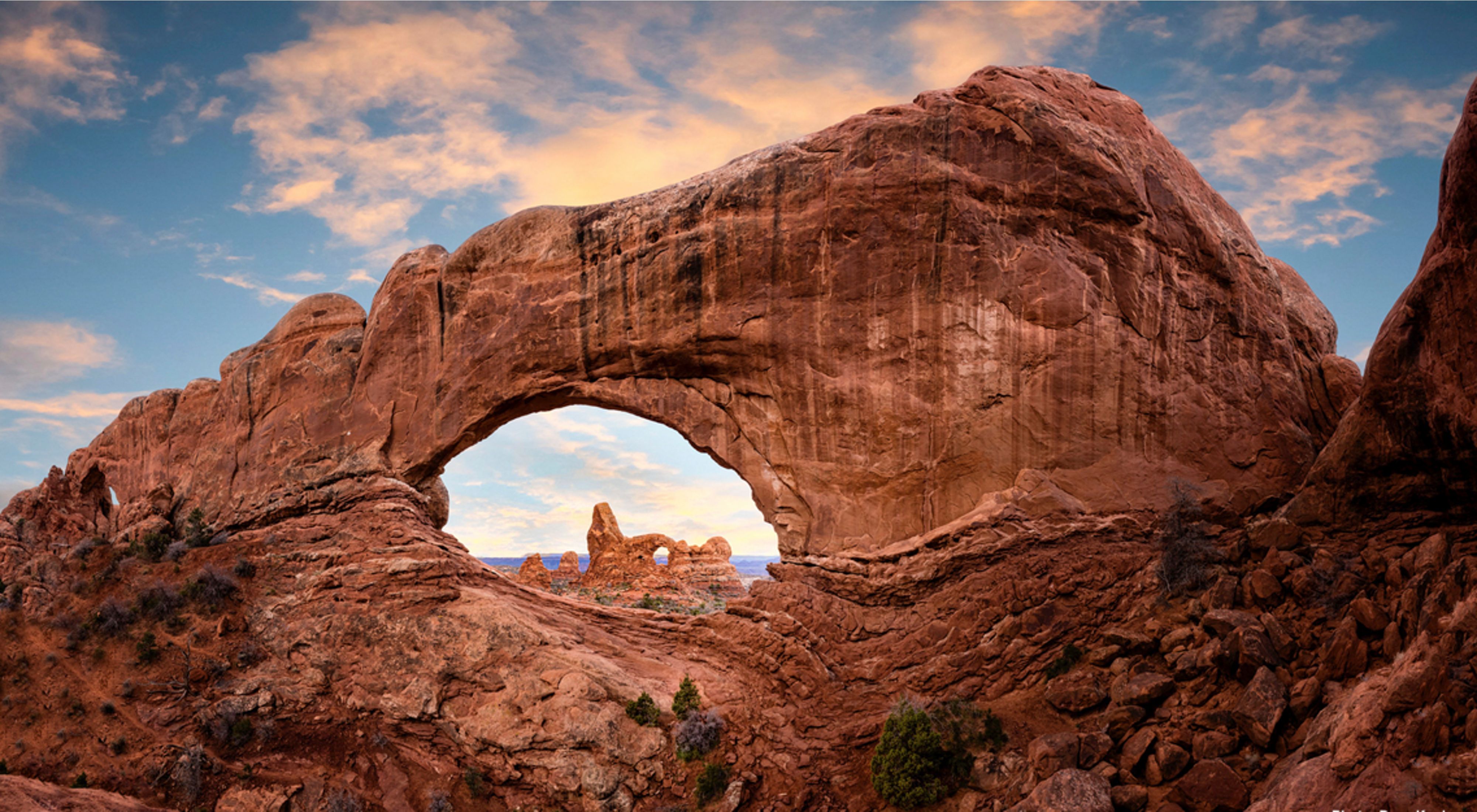 Sunrise at Arches National Park. Golden light touches rugged rock formations.