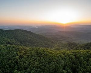 Expansive view of the sun setting over the Kentucky Appalachian Mountain region with a river running through a valley in the distance.