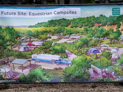 Un cartel presenta dibujos de campamentos recreativos, vehículos recreativos y caballos dentro de una arboleda.
