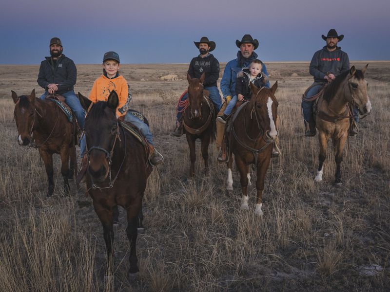 Group of people on horses at sunset.