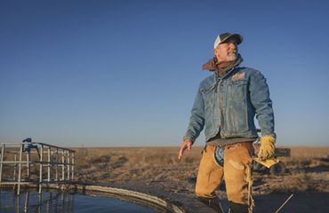 Rancher standing next to tank of water.