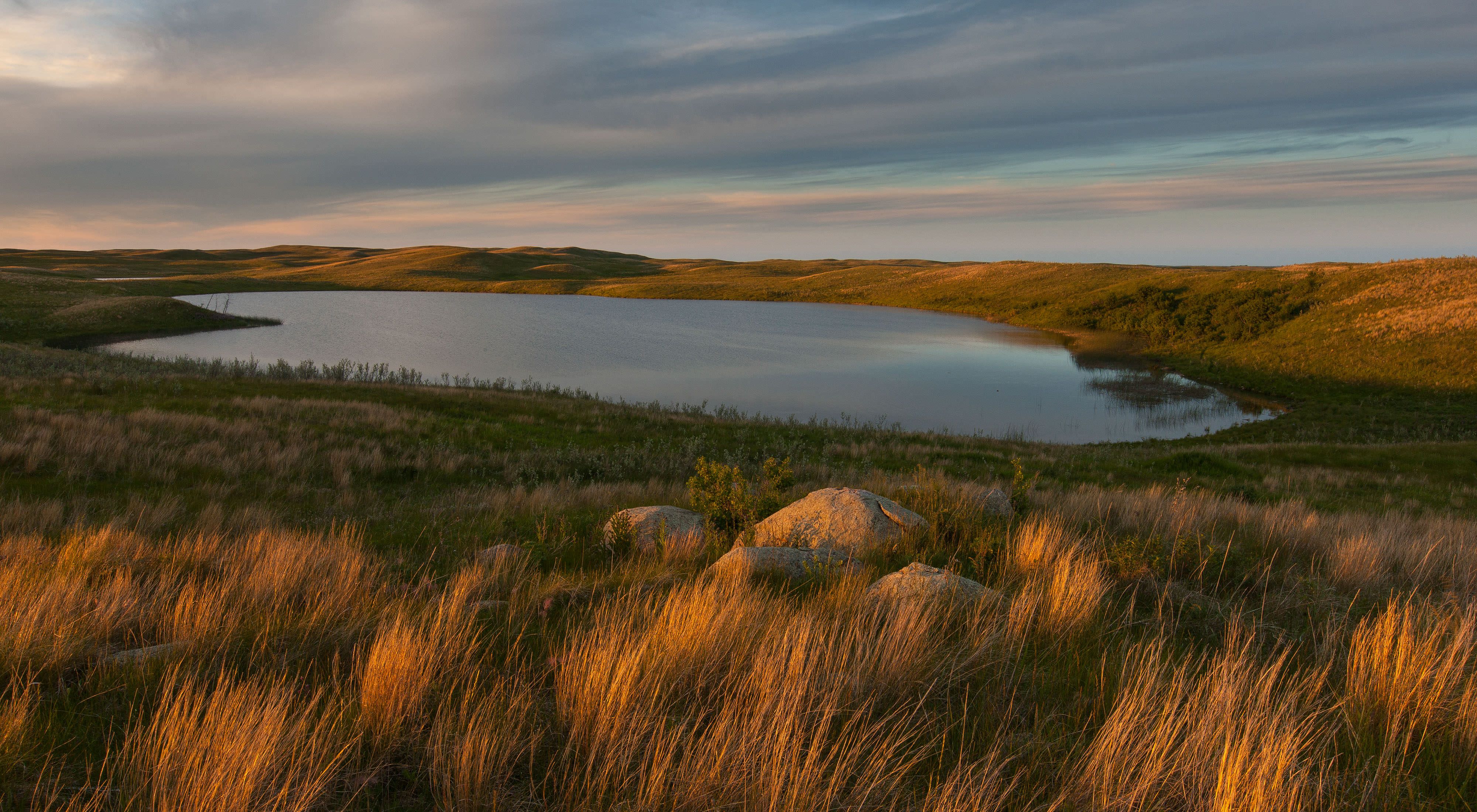 A small pond on a darkening prairie.