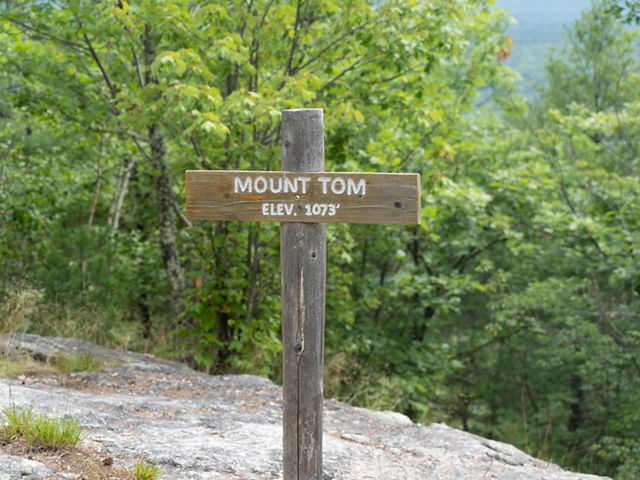 A wooden summit sign on a signpost reads Mount Tom elev. 1,073.