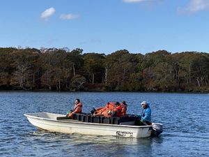 Podcast producer Jay Feinstein sits on a boat with several partners as they take crates of oysters to a restoration site in Katama Bay.
