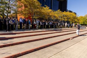 A large group of people pose for photos on steps.