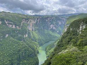 Landscape view of a large body of water with a rocky outcropping in the center and rocky, forested shores close on the left and in the distance.