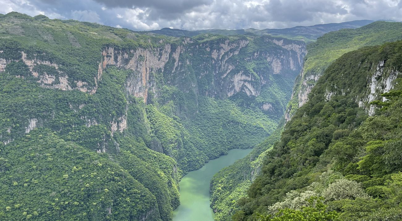 Landscape view of a large body of water with a rocky outcropping in the center and rocky, forested shores close on the left and in the distance.