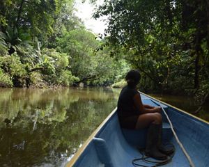 Mulher navegando em barco de um rio da Amazônia