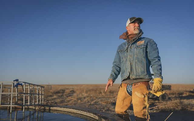 Rancher standing next to tank of water. 