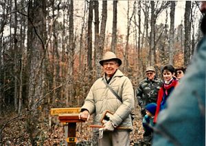 A man poses next to a wooden sign that reads, Nassawango Joe, during a trail dedication ceremony.