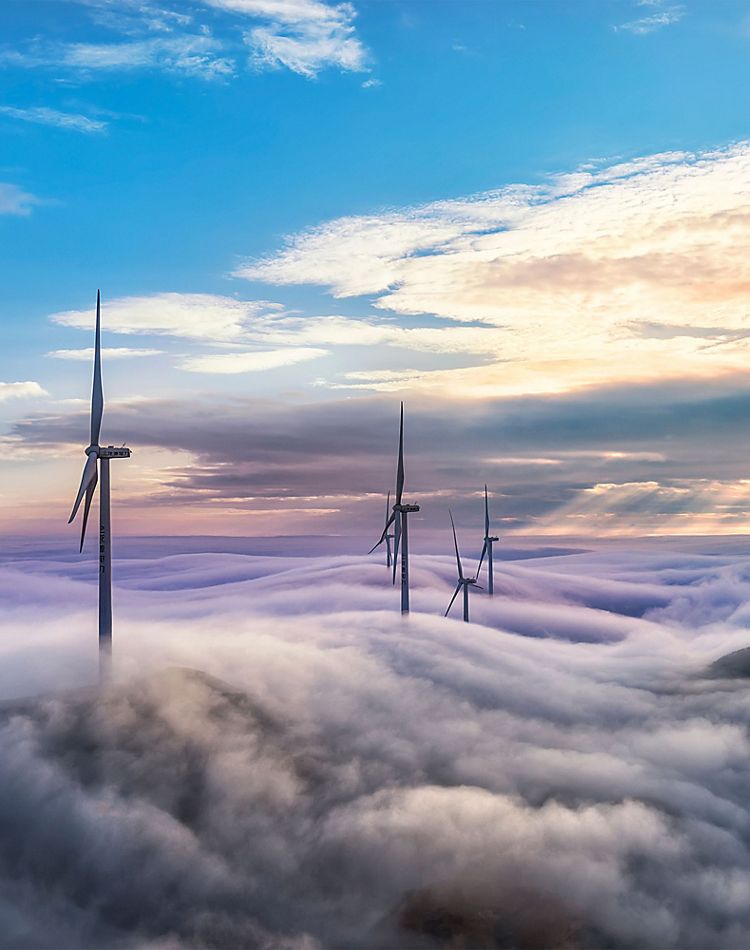 wind turbines poking up above low hanging clouds