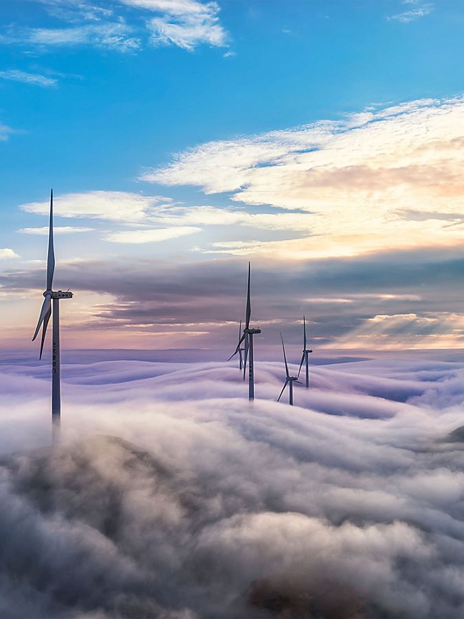 wind turbines poking up above low hanging clouds