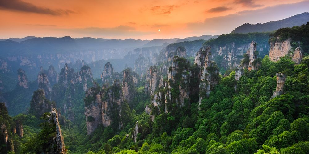 mountainous view of rock and greenery against a sunset sky