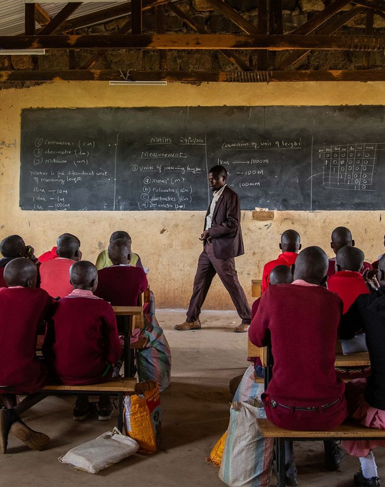a man stands at the front of a classroom of children