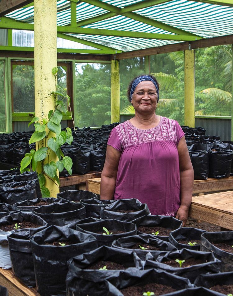 a smiling woman stands in plant nursery