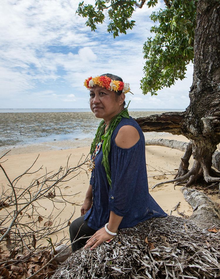 a woman sits along eroding coastline