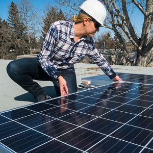 woman installs solar panel on a roof