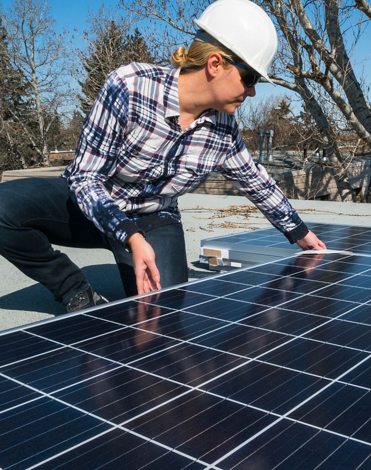 woman installs solar panel on a roof