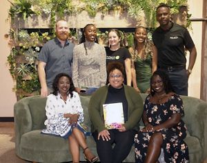 Five people standing and three people sitting on a couch and smiling.