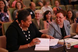 Women at a conference looking at each other smiling and talking.