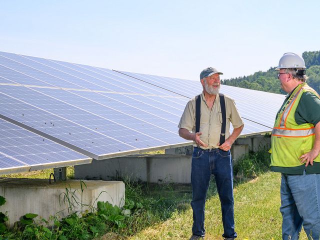 Landscape with two people in front of solar panels.