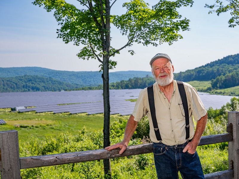 Man smiles at camera with a large solar array behind him in the background.