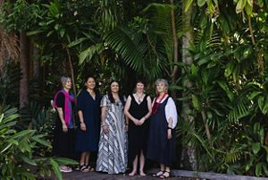 Five women post for a photo in front of a stand of tall trees.