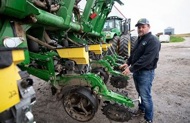 Bob Danes stands next to a large green no-till planter.