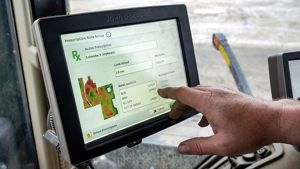 A hand points at a monitor that displays data related to soybean planting on an area of Danes Farms.